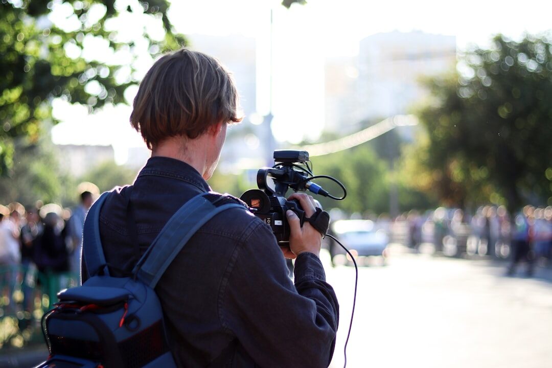 Video journalist filming a report outdoors with a professional camera